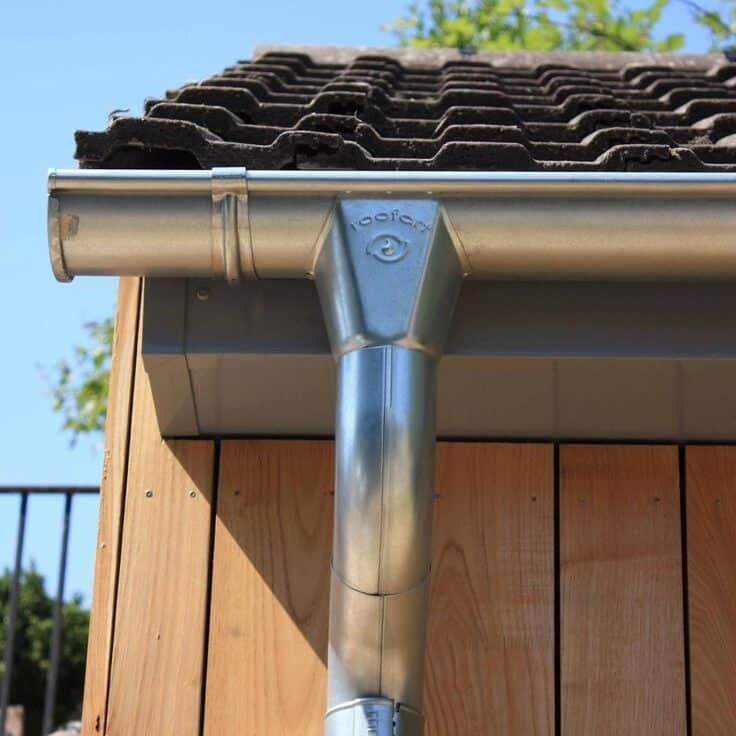 Sturdy Metal Gutter and Downspout System on a Tile Roof with Wooden Siding